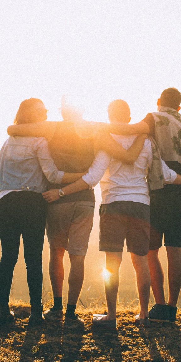 People with arms around each other looking towards the sun